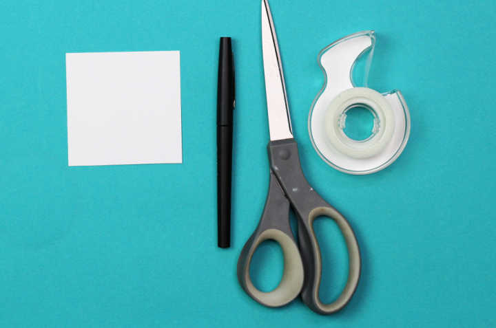   Quadratisches Papier, Stift, Schere und Rolle Klebeband