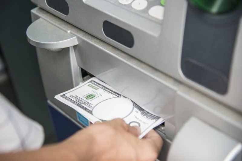 person som drar ut pengar från en bankomat
