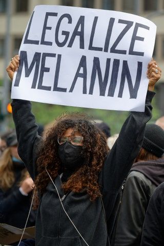 Un participante de las demostraciones silenciosas contra el racismo sostiene un cartel con las palabras Legalizar la melanina