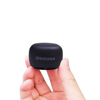 Mano sujetando un altavoz bluetooth negro de tamaño cuarto