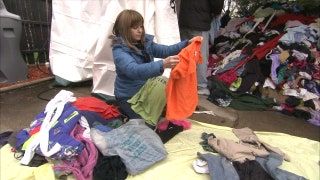 Una mujer ordena un montón de ropa sobre los acaparadores