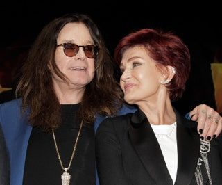Slika lahko vsebuje Ozzy Osbourne Človeška oseba, sončna očala, dodatki, dodatki, ogrlica, nakit, plašč in obleka