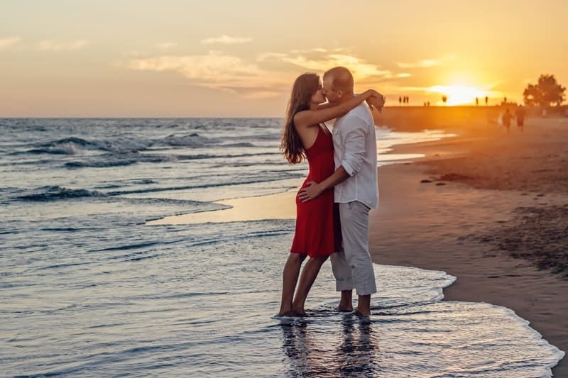 Pareja romántica besándose durante la noche en la playa.