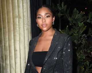 Jordyn Woods trägt eine schwarze Paillettenjacke und ein schwarzes Bandeau-Top.
