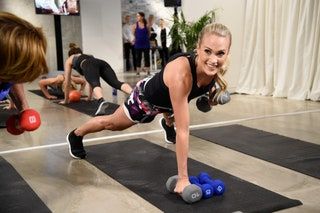 Carrie Underwood hebt Gewichte in Plankenposition auf einer Gymnastikmatte.