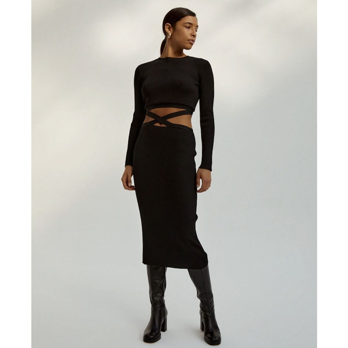 modelo con vestido negro de manga larga con cortes en la cintura