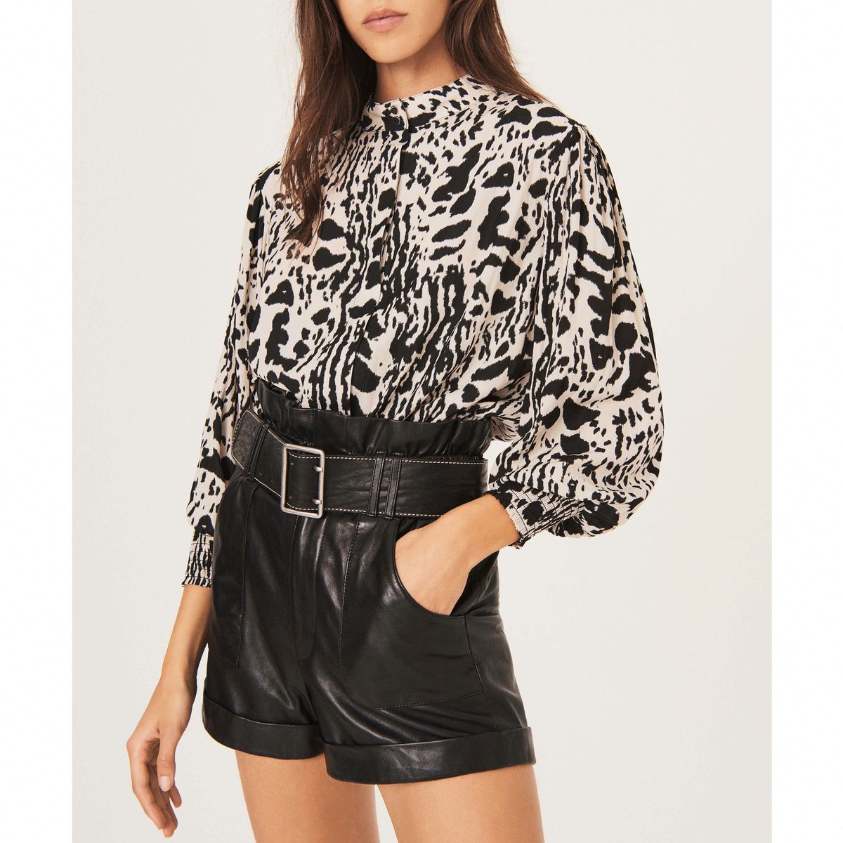 modelo vistiendo blusa blanca y negra con pantalones cortos de cuero negro
