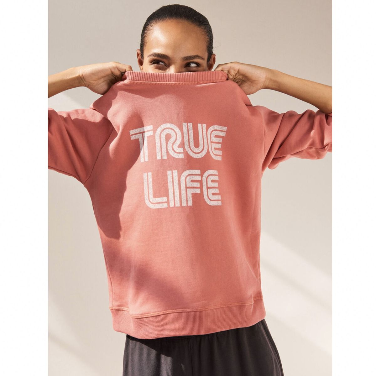 modelo vistiendo sudadera rosa con texto blanco