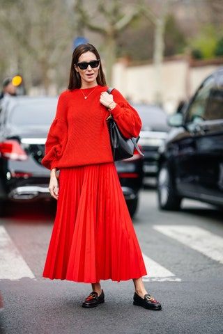 Frau mit rotem Pullover mit rotem Rock und schwarzen Slippern