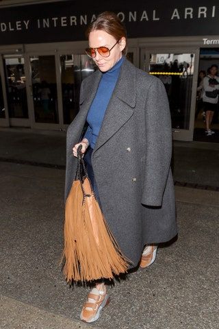 女性は特大のコートを含む空港の衣装を着ています