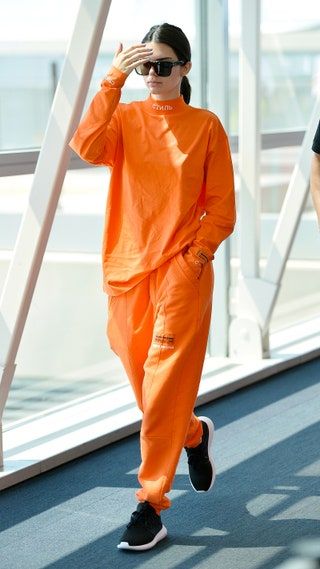 空港でオレンジ色の服を着たケンダル・ジェンナー