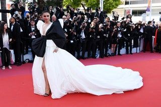 Deepika Padukone con un vestido blanco de manga larga con una cola dramática y un lazo negro en la parte delantera en el Cannes rojo ...