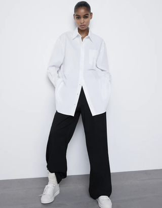 modelo vistiendo blusa blanca con pantalones negros