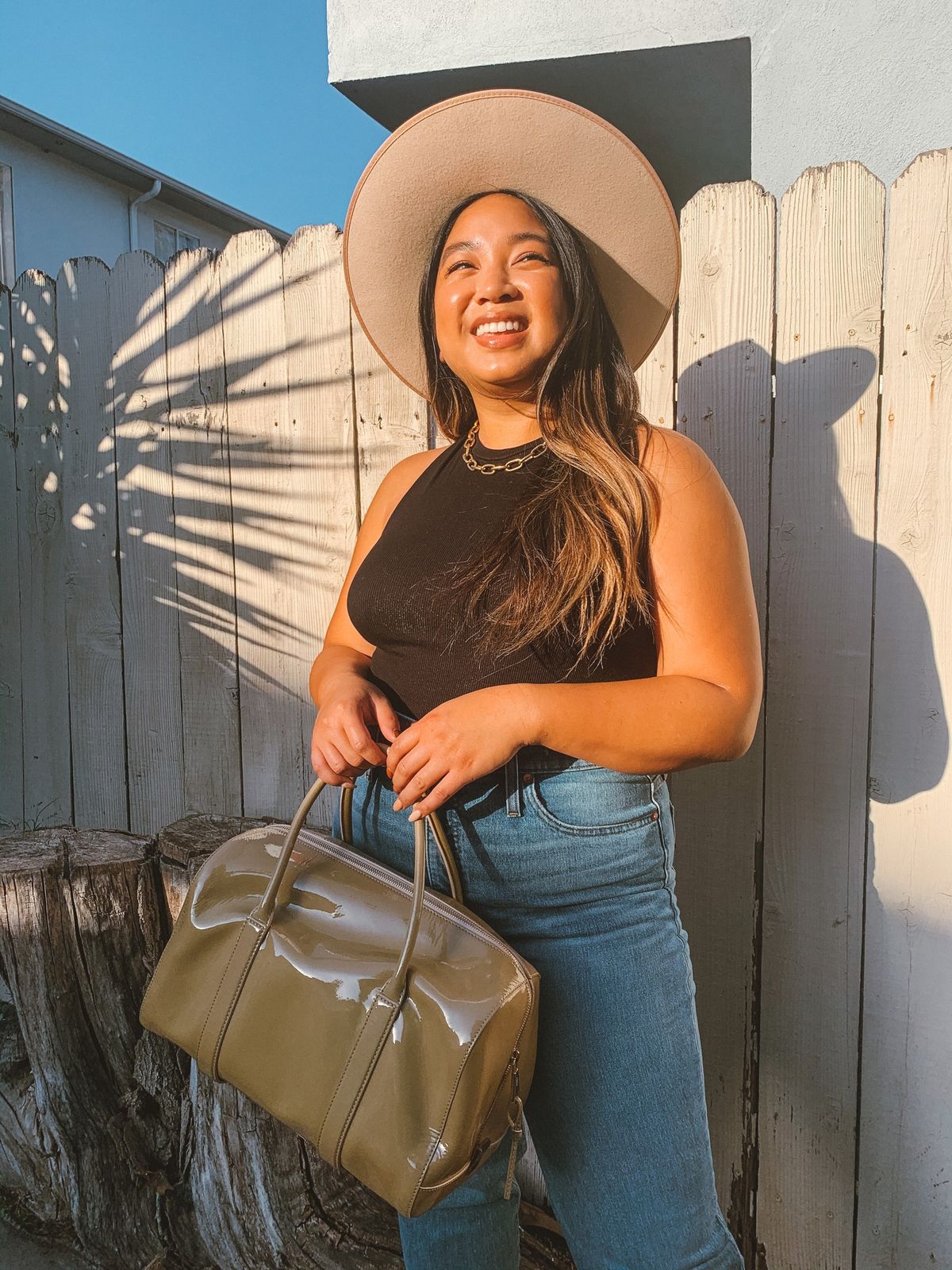 mujer sonriente, llevando, sombrero, tanque, jeans, y, bolso