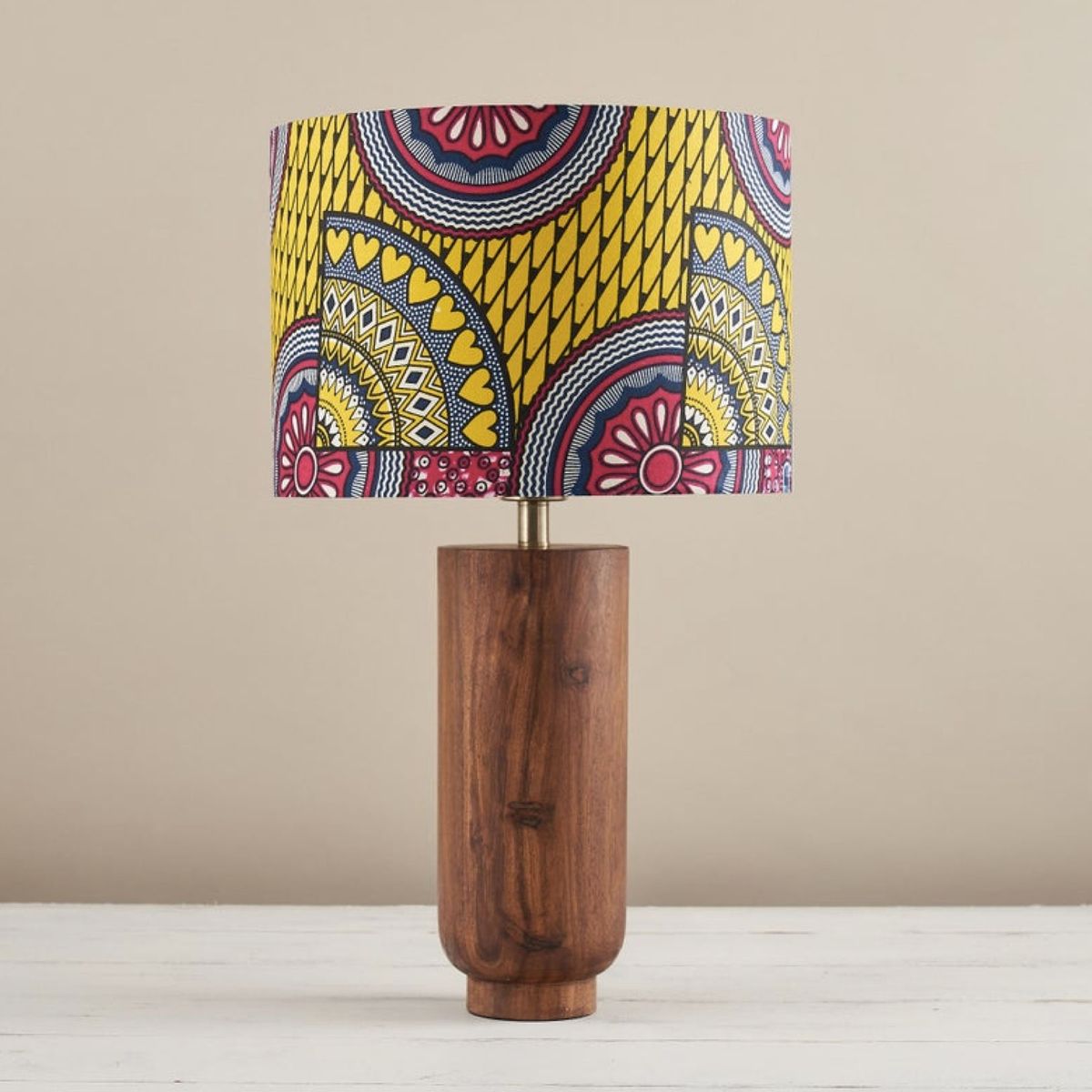 Pantalla de lámpara estampada en amarillo, rosa y azul sobre soporte de lámpara de madera