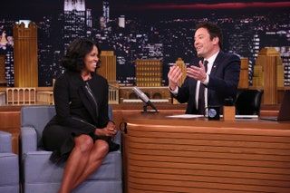 Bilden kan innehålla Jimmy Fallon Människoperson Michelle Obama Rum inomhus Kappa Kostym Kläder Överrock och kläder